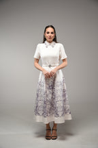 Woman wearing a white dress with floral patterns on a gray background